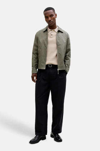 Beige geribbelde poloshirt van PREMIUM by JACK & JONES, gedragen onder een open groen jasje met zwarte broek en lakschoenen.