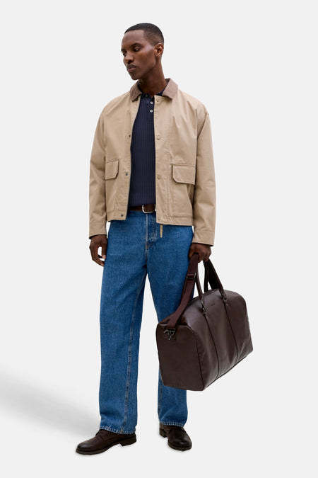 Donkerblauwe geribde trui met ronde hals van PREMIUM by JACK & JONES, gedragen onder een open beige jas.