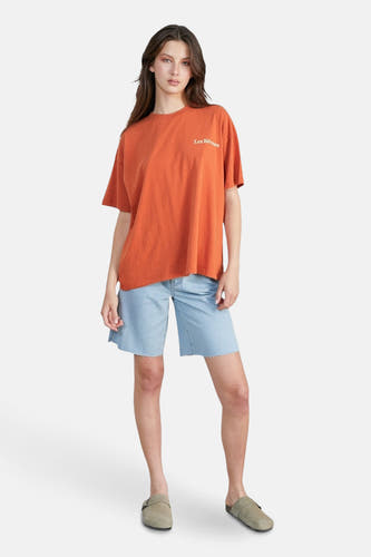 T-shirt orange à manches courtes de 24 couleurs, porté avec des shorts en denim et des mocassins en cuir.
