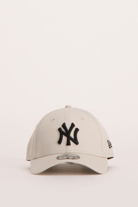 Chapeau beige de NEW ERA, avec un logo brodé sur le côté, en vue latérale.