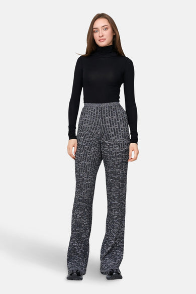Zwart shirt met lange mouwen van 24 colours gmbh, gedragen met een gemêleerde pantalon met grafisch patroon.
