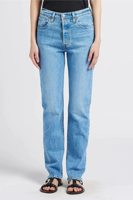 Jean droit bleu clair de Levi's, vu de derrière, associé à une hoodie crème et une beanie verte.