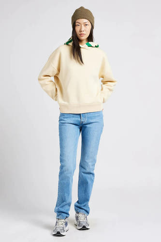 Lichtblauwe straight jeans van Levi's, gecombineerd met een crèmekleurige hoodie en een groene muts.
