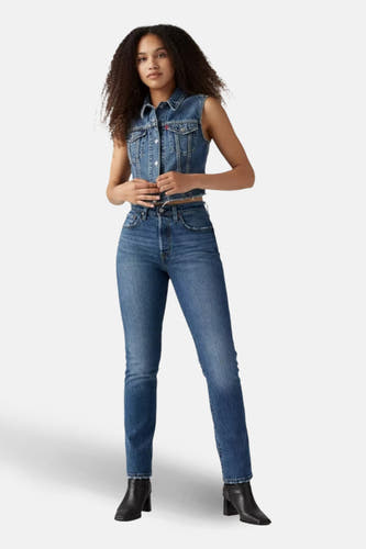 Jean droit en denim bleu de Levi's, arrière, combiné avec un gilet en denim et des bottes noires.