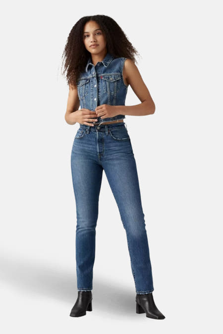 Jeans straight mid blue denim van Levi's®, gecombineerd met denim vest en zwarte laarsjes.