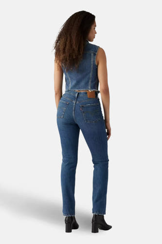 Rechte jeans van blauw denim van Levi's, achterkant, gecombineerd met denim vest en zwarte laarzen.