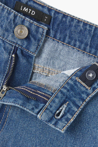 Jean décontracté de LMTD en denim bleu moyen, avec une ceinture ajustable et un zip.