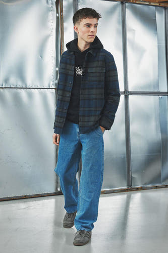 Jean décontracté de LMTD en denim bleu clair, associé à une hoodie noire et un chemisier rayé.