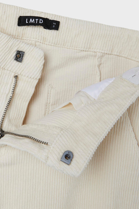Pantalon beige de LMTD, avec une texture corduroy et une fermeture à glissière métallique, gros plan rapproché.