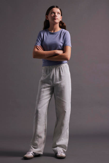 T-shirt bleu à manches courtes de LMTD, porté avec un pantalon rayé et des baskets.