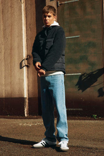 Zwarte korte jas van LMTD, gedragen met een wit T-shirt, jeans en sneakers.
