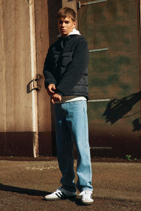 Zwarte korte jas van LMTD, gedragen met een wit T-shirt, jeans en sneakers.