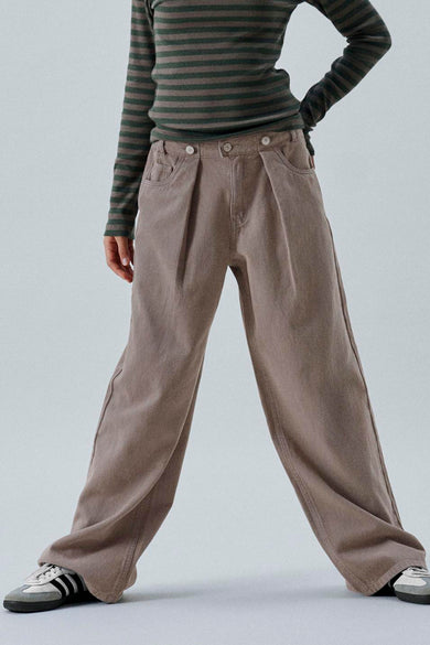 Pantalon brun de LMTD, avec plis et larges jambes, associé à une chemise rayée et des baskets.