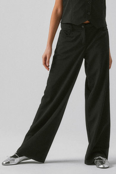 Jean noir de LMTD, avec des jambes larges et porté avec des ballerines argentées.