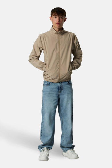 Lichtblauwe wijde jeans van LMTD, gecombineerd met een beige jas en witte sneakers.