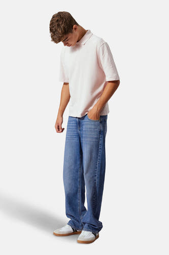 Jean droit bleu clair denim de LMTD, porté avec un t-shirt rose et des baskets blanches.