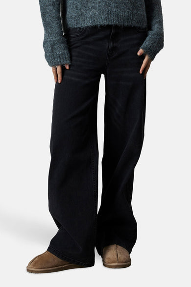 Zwarte wijde jeans van LMTD, gecombineerd met een blauwgrijze trui en bruine schoenen.