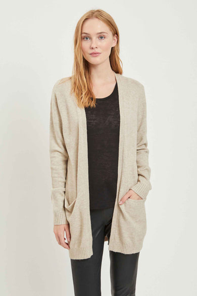 Beige vest van VILA, met zakken en gedragen over een zwart shirt en een zwarte broek.