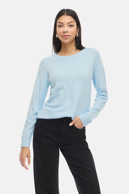 Blauwe trui met ronde hals van VILA, gedragen met een zwarte broek en zilveren oorbellen.
