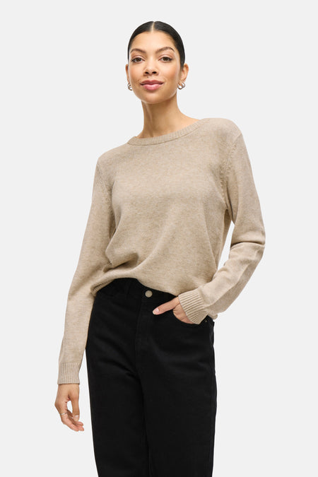 Beige trui met ronde hals van VILA, gedragen met zwarte broek en zilveren oorbellen.