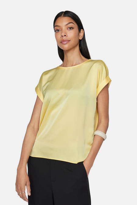 Geel T-shirt met korte mouwen van VILA, met omgeslagen mouwen en gecombineerd met een zwarte broek.
