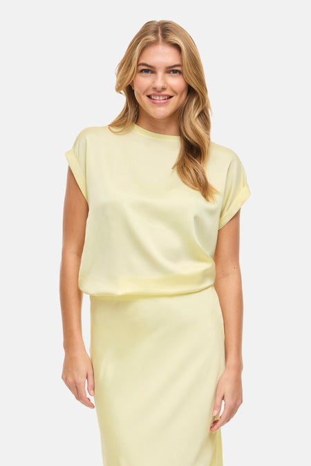 T-shirt à manches courtes jaune de VILA®, combiné avec une longue jupe jaune et des talons noirs.
