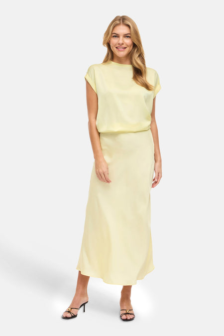 Gele T-shirt met korte mouwen van VILA®, gecombineerd met een lange, gele rok en zwarte hakken.