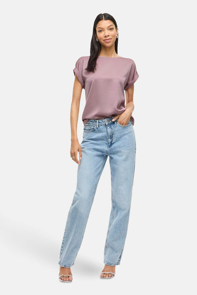Roze T-shirt met korte mouwen van VILA®, gedragen met jeans en zilveren sandalen.

