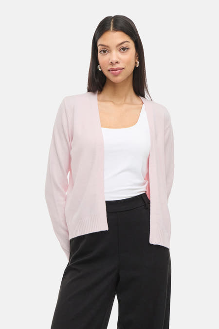 Roze vest van VILA®, gedragen over een wit hemd en een zwarte broek.
