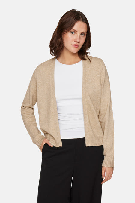 Beige vest van VILA, gedragen over een wit shirt en gecombineerd met een zwarte broek.
