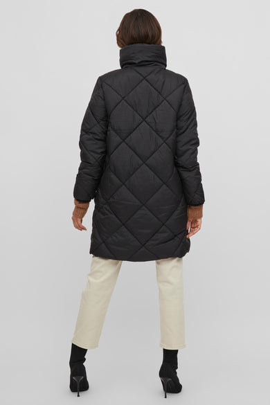 Zwarte pufferjas met ruitpatroon van VILA®, achterzijde, hoge kraag, model draagt crèmekleurige broek en zwarte laarzen