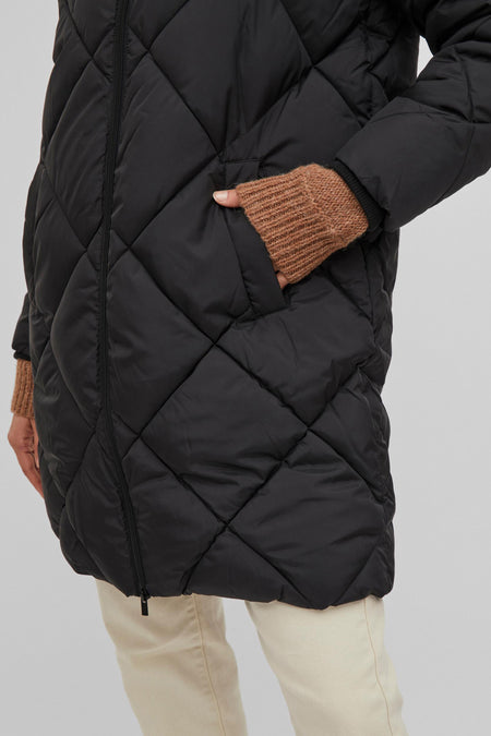 Zwarte pufferjas met ruitpatroon van VILA®, zijprofiel, hand in zak, gebreide mouwuiteinden, lichte broek