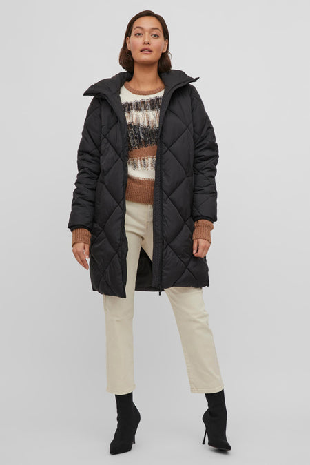 Zwarte pufferjas met ruitpatroon van VILA®, model draagt gestreept trui en crèmekleurige broek, front view