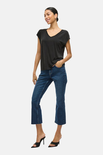 T-shirt noir de VILA, à manches courtes, associé à des jeans bleus et des baskets noires à talons.