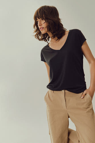 T-shirt noir à manches courtes de VILA®, associé à un pantalon beige et une pose décontractée.