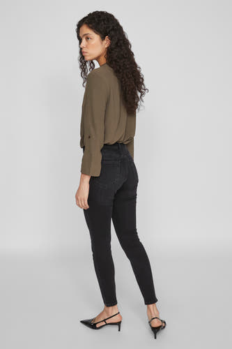 Zwarte skinny jeans van VILA, met hoge taille en gedragen met een olijfkleurige blouse en zwarte hakken.
