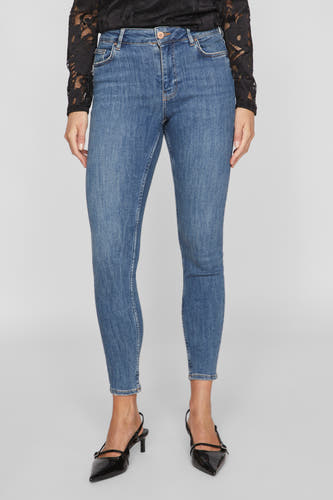 Middenblauwe skinny jeans van VILA, met een aansluitende pasvorm en gedragen met zwarte hakken en een kanten top.
