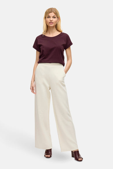 Paars T-shirt met korte mouwen van VILA®, gedragen met crèmekleurige, wijde broek en open schoenen.