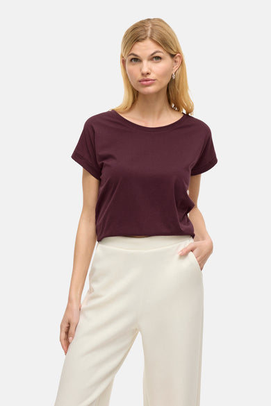 Paars T-shirt met korte mouwen van VILA®, gedragen met een witte broek en zilveren oorbellen.