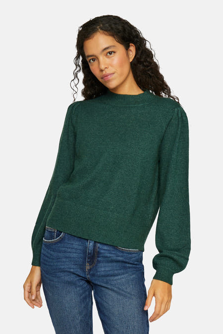 Groene trui met rolkraag van VILA, met lange mouwen en gecombineerd met een blauwe jeans.