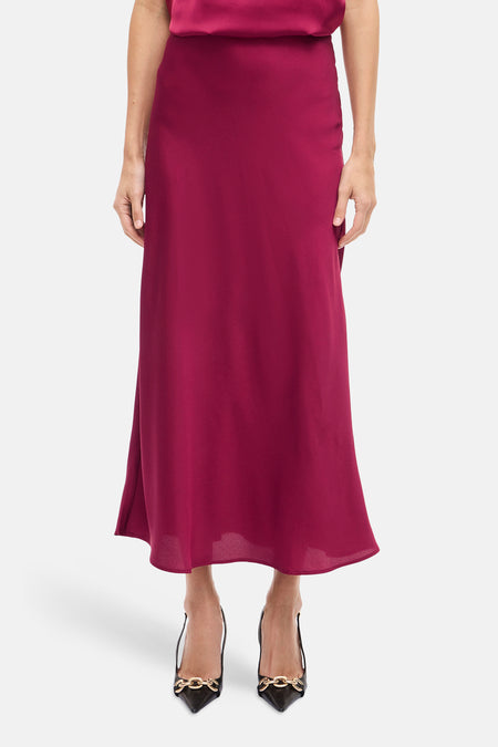 Lange bordeaux rok van VILA®, met een vloeiende, elegante stijl en gecombineerd met zwarte pumps met goudkleurige details.
