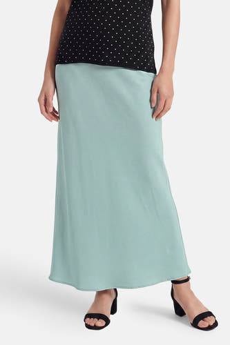 Lange lichtblauwe rok van VILA®, gemaakt van een vloeiende effen stof, gedragen met een zwarte top met stippen en zwarte sandalen.