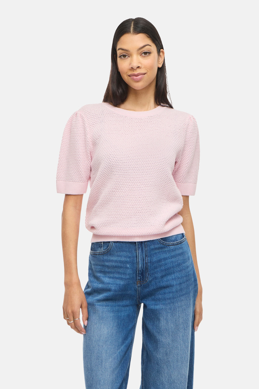 Pull rose de VILA® à manches courtes et à texture tissée, combiné avec un jean ample et des talons noirs.
