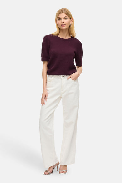 Paarse trui van VILA®, met korte mouwen, gecombineerd met een witte jeans en zilveren sandalen.