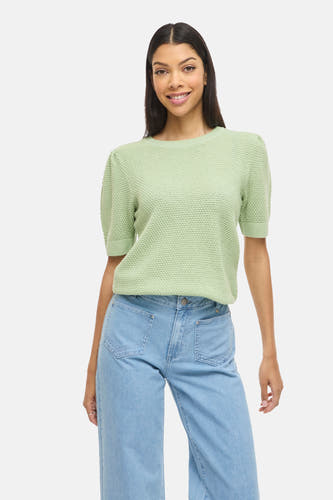 Groene trui van VILA®, met korte mouwen en een fijn gebreide textuur, gecombineerd met blauwe jeans.
