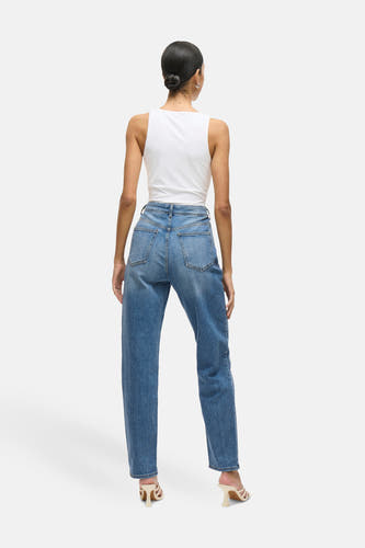 Jean VIKELLY en denim bleu moyen de VILA®, avec des jambes droites, porté avec un tank-top blanc et des baskets crème, vue arrière.