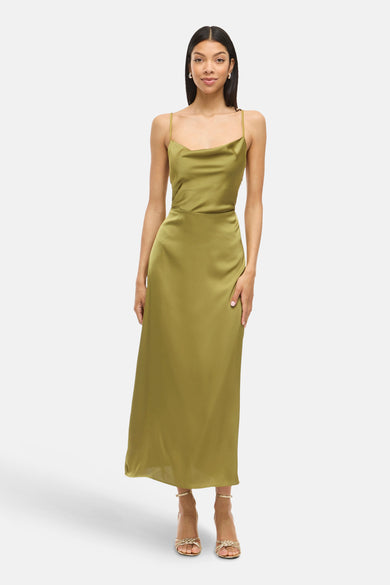 Groene mouwloze kleedje van VILA, met een satijnen textuur en dunne bandjes, gedragen met gouden sandalen.
