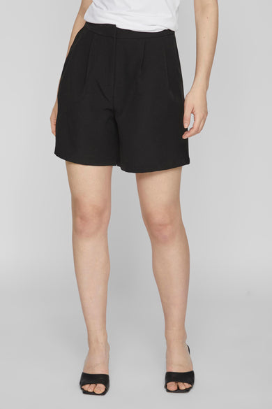 Zwarte short van VILA, met plooien en een wijde pijp, gecombineerd met zwarte muiltjes.
