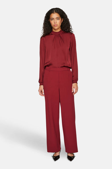 Jean rouge de VILA®, associé à une blouse bordeaux avec des manches longues et des chaussures noires.