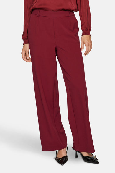 Pantalon rouge de VILA®, avec des jambes larges et associé à une blouse et des chaussures noires.
